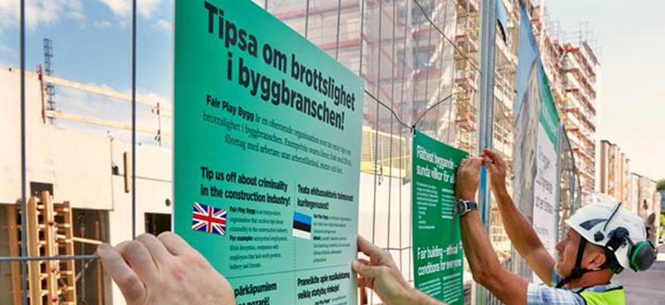 Våra medarbetare sätter upp skyltar med information om Rättvist byggande på olika språk.